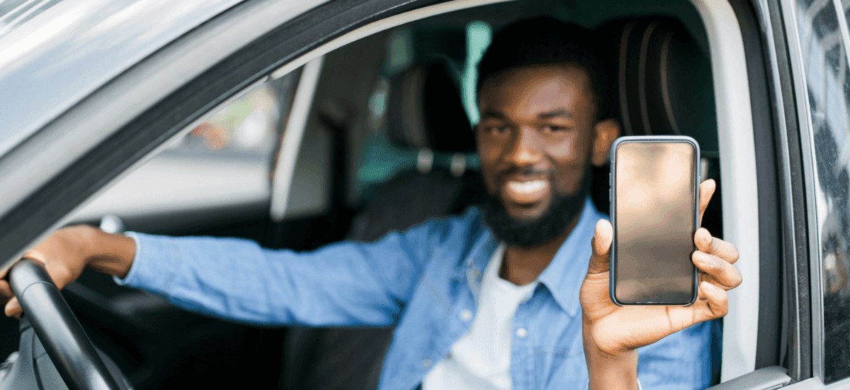 Illustrative e-hailing driver holding a mobile phone from inside a vehicle